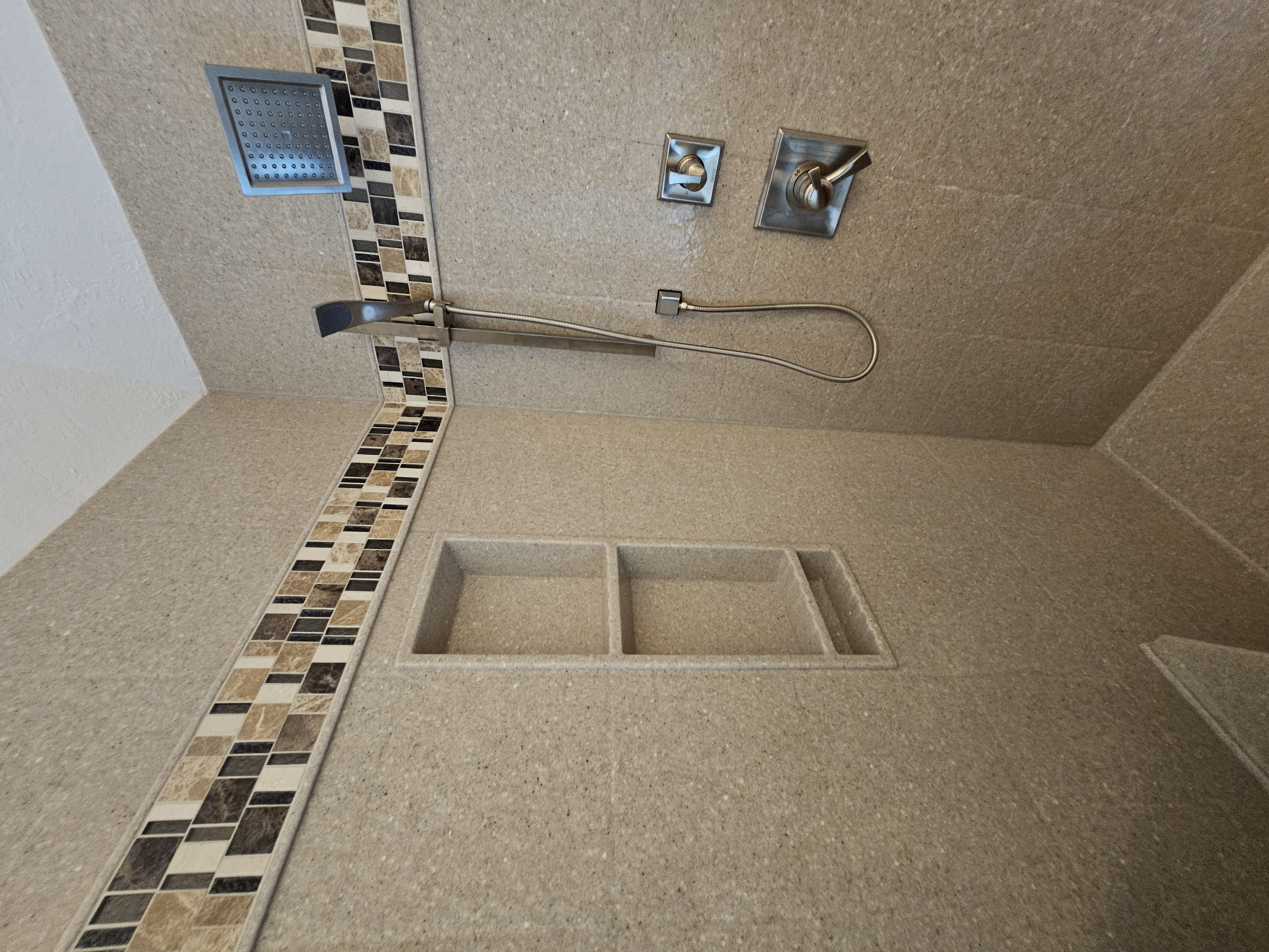Custom solid stone panel corner shower with mosaic tile border and custom glass enclosure
