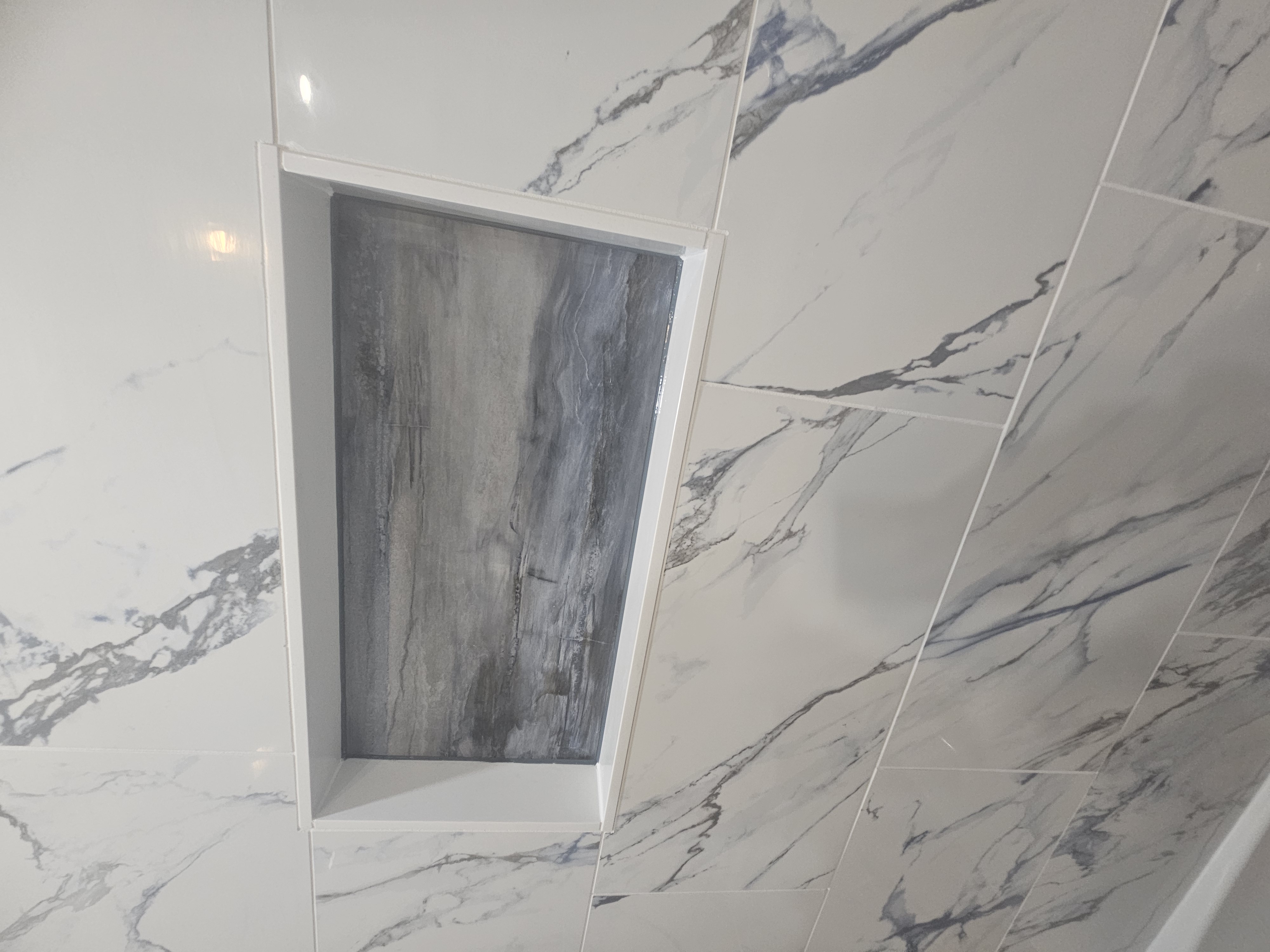 Marbled porcelain tile shower install with custom niche