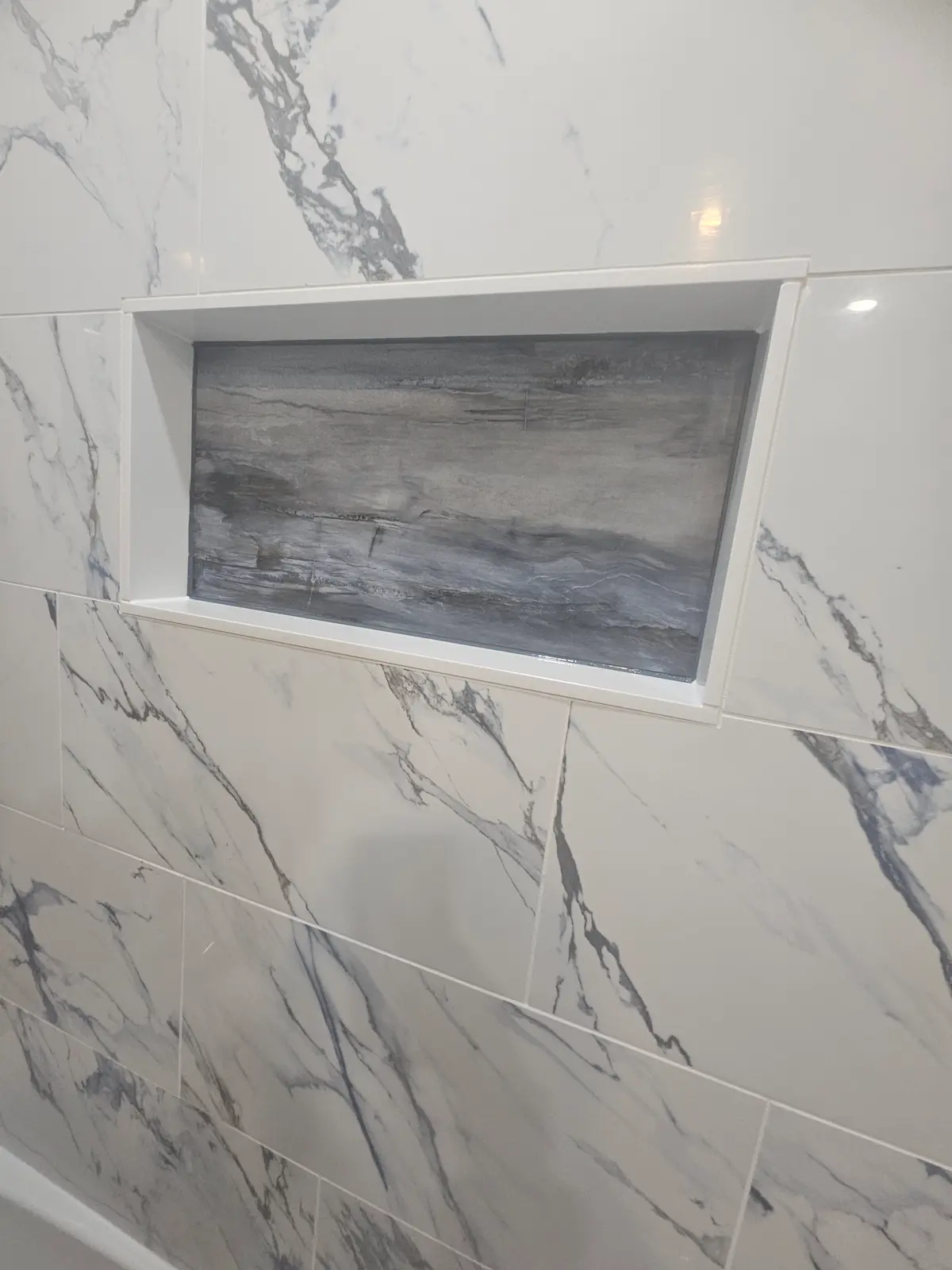 Marbled porcelain tile shower install with custom niche